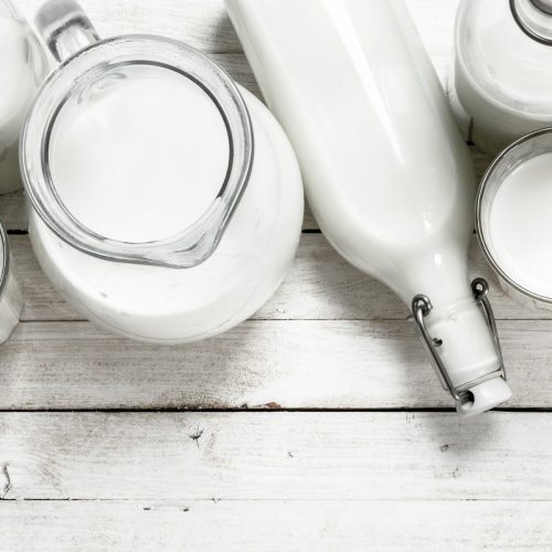 jars of milk on white wood table.
