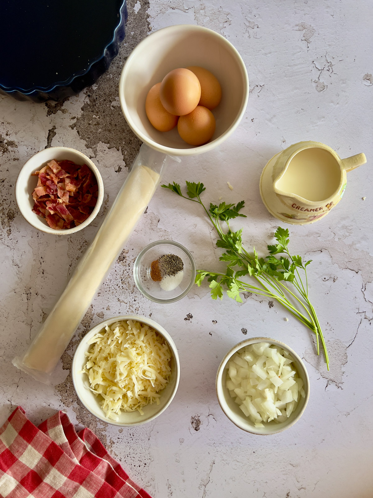 Eggs, Crumbled bacon, parsley, creamer of half n half, onions and shredded cheese on concrete surface.