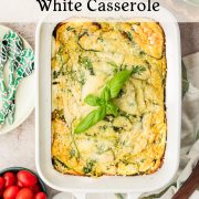A crustless egg white spinach quiche with baked ricotta in a white dish, garnished with fresh basil. Nearby are grape tomatoes, patterned forks, and a striped cloth on a light countertop. Text describes the recipe.